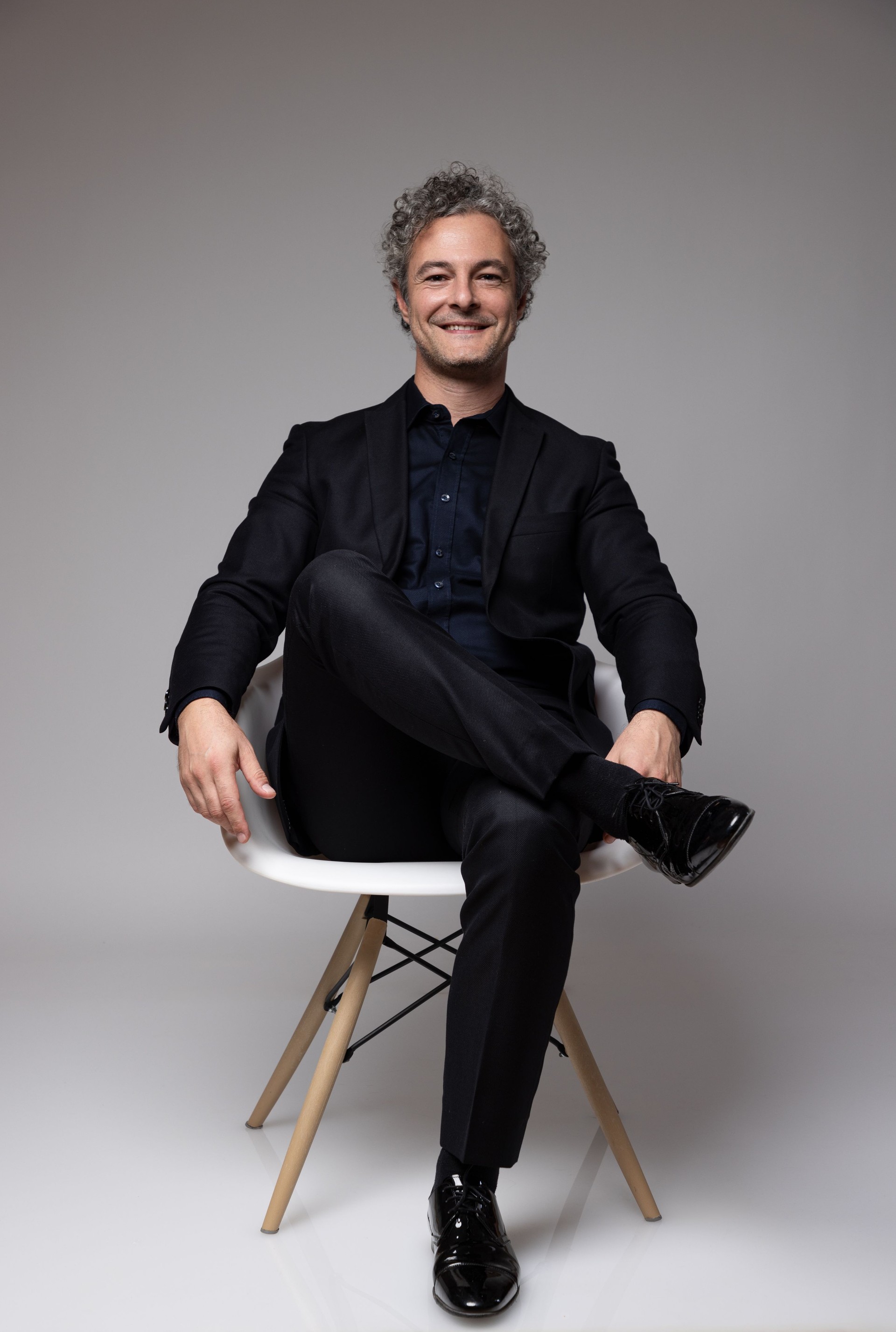 Confident businessman sits in a chair and looks at the camera with a smile